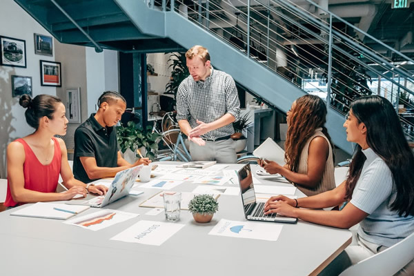 Equipo de marketing en una oficina reunidos alrededor de una mesa con papeles.